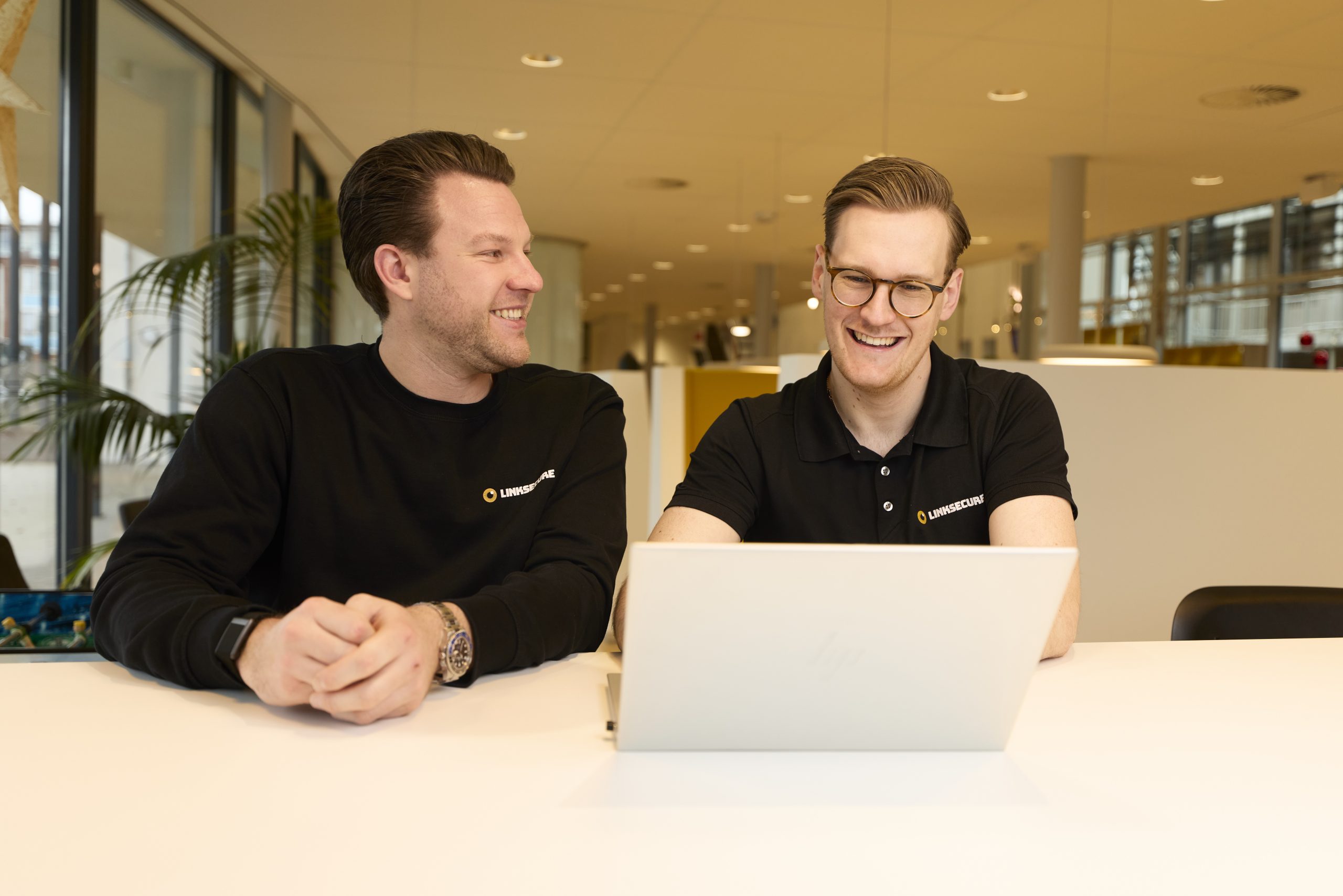 LinkSecure security officers aan het werk achter laptop lachend